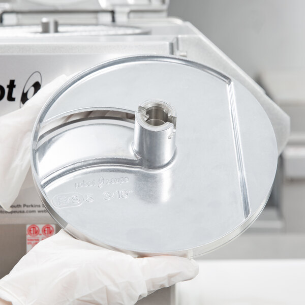 A person in gloves holding a circular metal Robot Coupe LP5DISC.