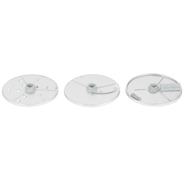 A Robot Coupe 3-disc set for a food processor with a white circular metal disc with a hole, a white circular metal disc with holes, and a circular silver metal disc.