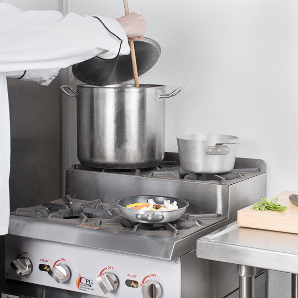 A person cooking food on a Cooking Performance Group gas range.