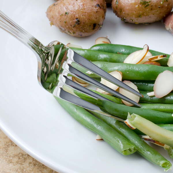 A Walco Pacific Rim stainless steel dinner fork on a plate of green beans and potatoes.