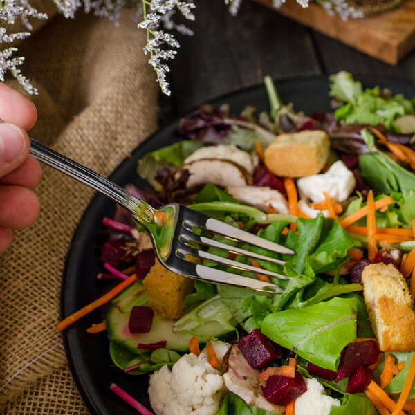 A Walco Luxor stainless steel salad fork in a plate of vegetable salad.