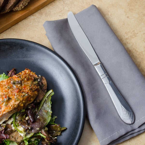 A plate of food with a Walco Art Deco stainless steel dinner knife on a table.