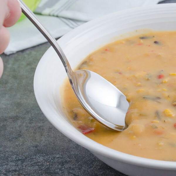 A Walco Luxor stainless steel bouillon spoon in a bowl of soup.