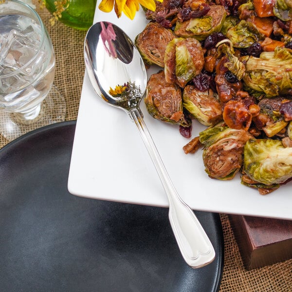 A plate of food with a Walco Luxor serving spoon and a glass of water.