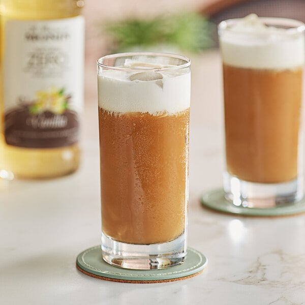 Two glasses of iced coffee with Monin Zero Calorie Natural Vanilla Flavoring Syrup on coasters.