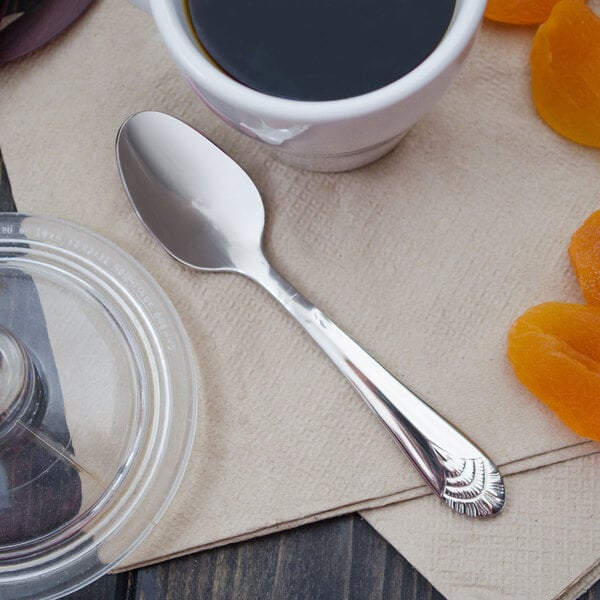 An Art Deco Walco demitasse spoon next to a cup of coffee.