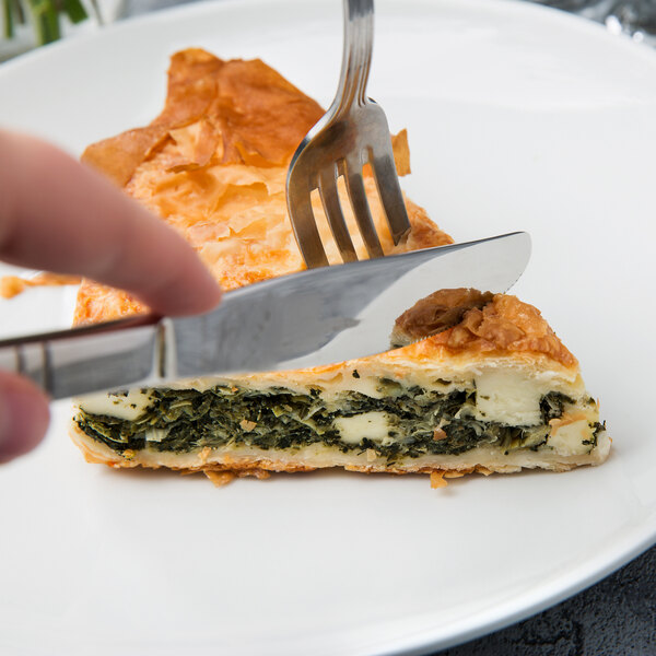 A person using a Walco Art Deco stainless steel knife to cut a piece of food.