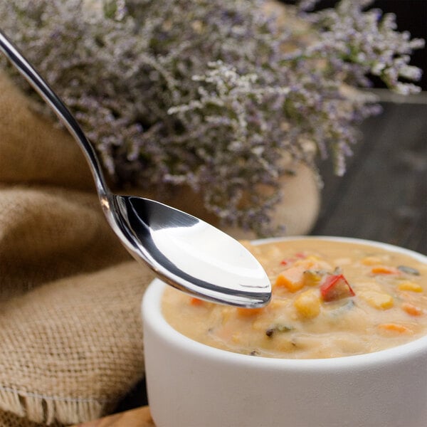 A Walco stainless steel bouillon spoon in a bowl of soup.