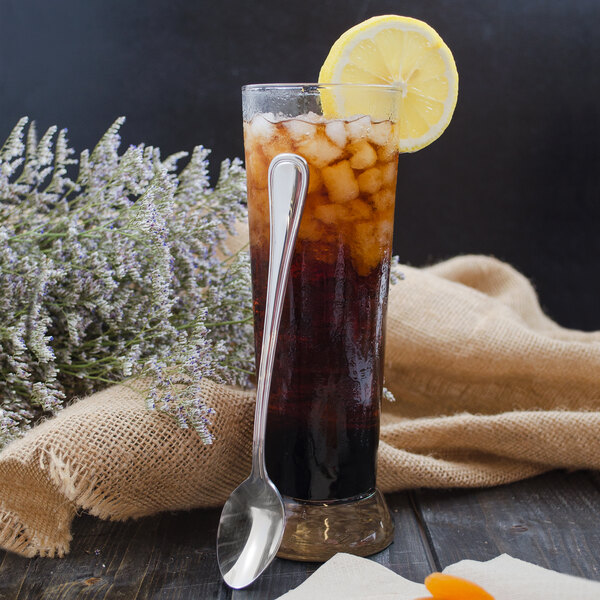 A glass of iced tea with a lemon slice and a Walco Pacific Rim stainless steel iced tea spoon.