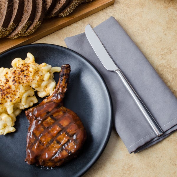 A plate of food with a Walco Erik stainless steel knife next to a fork.