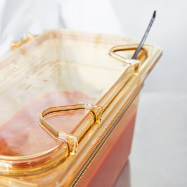 A Carlisle amber plastic container lid with one notch for a spoon.