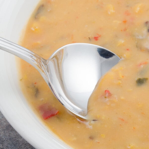 A Walco stainless steel bouillon spoon in a bowl of soup.