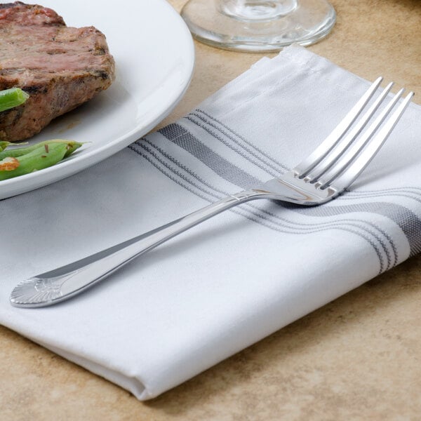 A Walco Meteor stainless steel dinner fork on a white plate with a piece of meat.