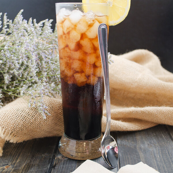 A glass of iced tea with a lemon slice and a Walco stainless steel iced tea spoon.