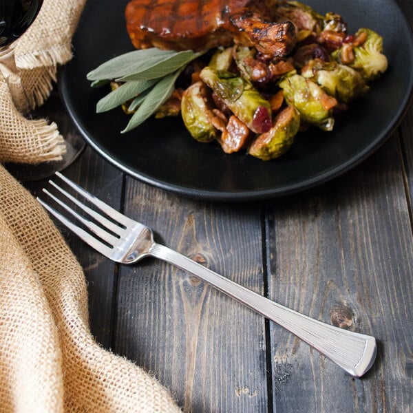A plate of food with brussels sprouts and bacon next to a Walco Bosa Nova table fork.