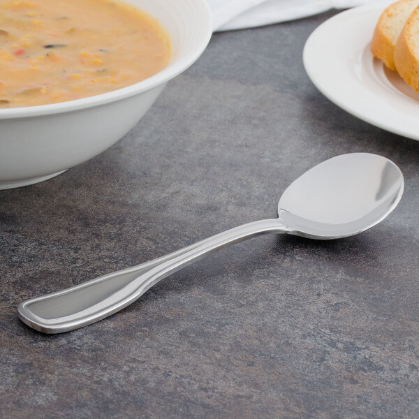 A Walco Saville bouillon spoon in a bowl of soup on a table.