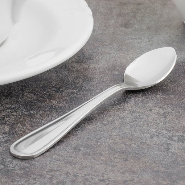 A Walco stainless steel demitasse spoon on a table.