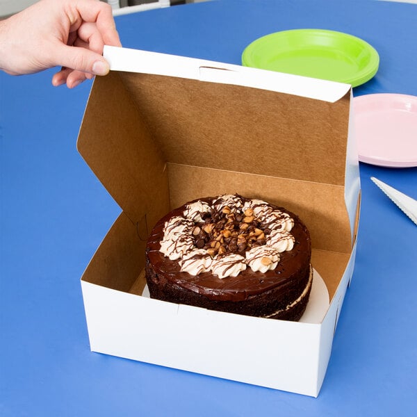 Small white cake box with a cake within