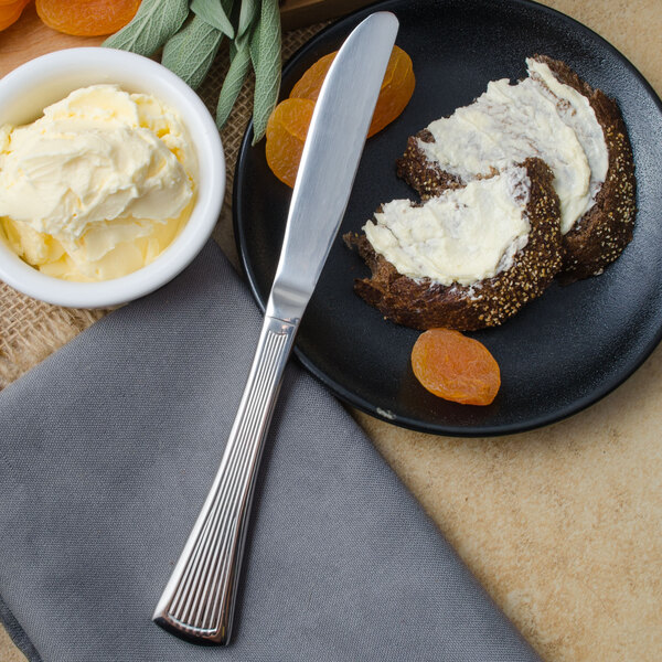 A plate with food and a Walco Bosa Nova butter knife on it.