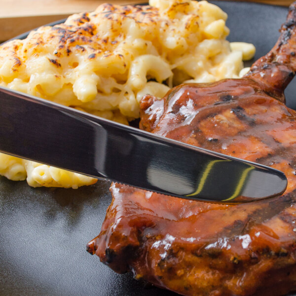 A plate of food with a Walco Danish Pride dinner knife cutting meat.