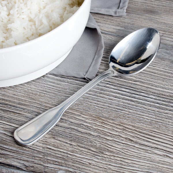 A Walco stainless steel serving spoon in a bowl of rice on a table.