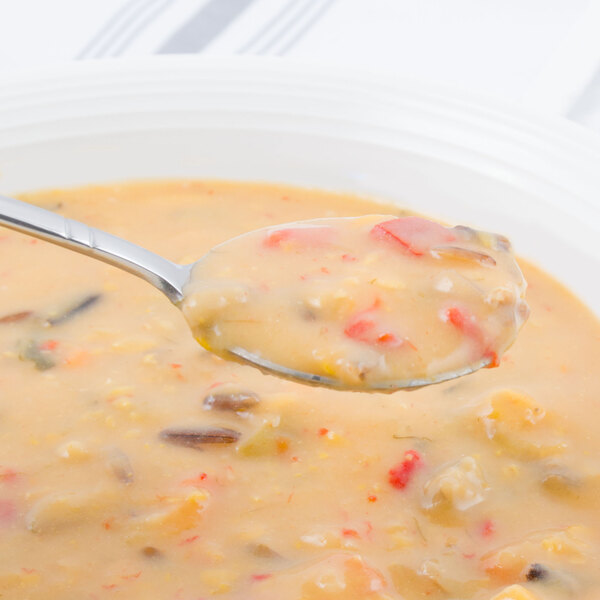 A Walco stainless steel bouillon spoon in a bowl of soup.