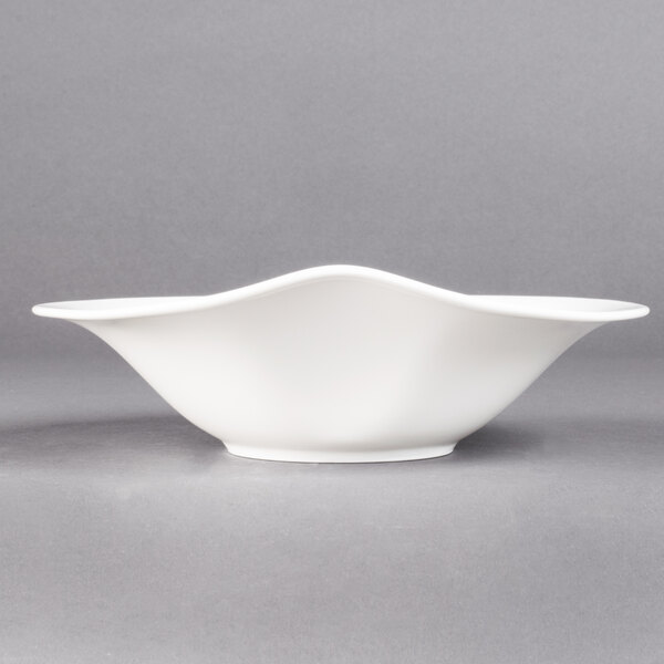 A Villeroy & Boch white porcelain deep bowl with a curved edge on a gray background.