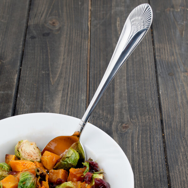 A Walco stainless steel serving spoon in a bowl of salad.