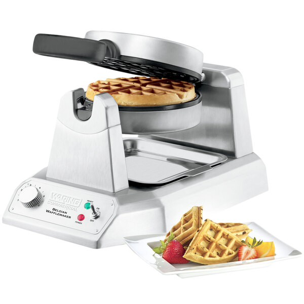 Single Waring waffle maker opened with cooked Belgian waffle inside next to plate of waffles