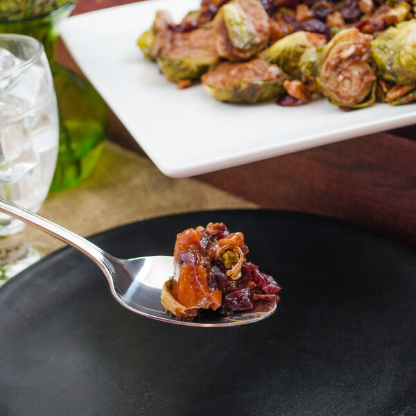 A Walco stainless steel serving spoon full of food on a plate.