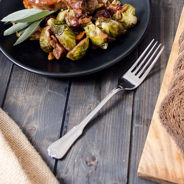 A Walco Barony stainless steel table fork on a plate of food.