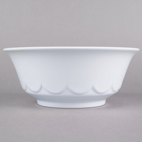 A close-up of a white Thunder Group melamine bowl with a scalloped edge.