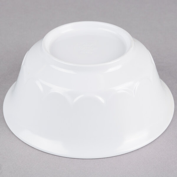 A white bowl with a scalloped edge on a gray surface.