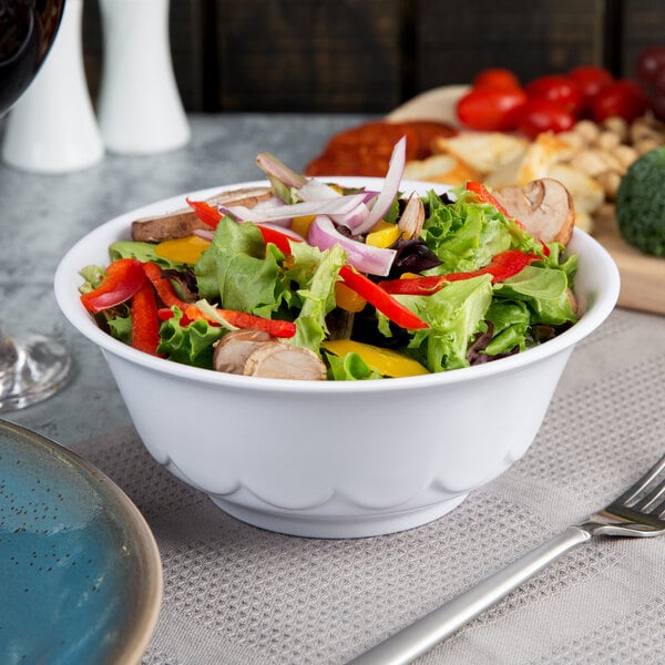 A white melamine bowl filled with salad and vegetables with a fork.