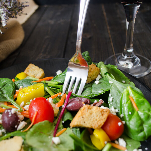 A Walco Marcie stainless steel salad fork on a plate of salad.