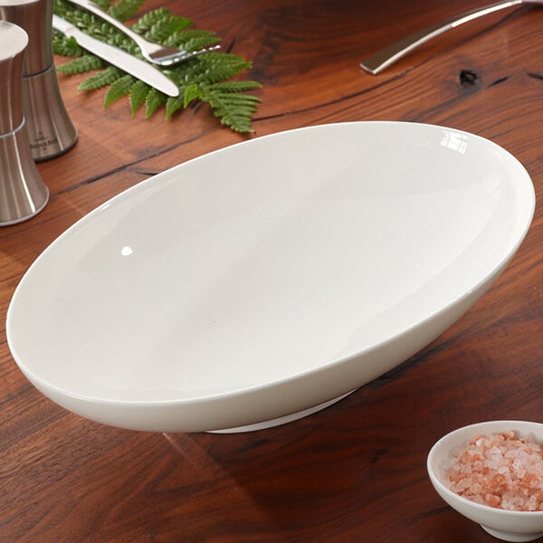 A white oval Villeroy & Boch porcelain bowl on a wood surface.