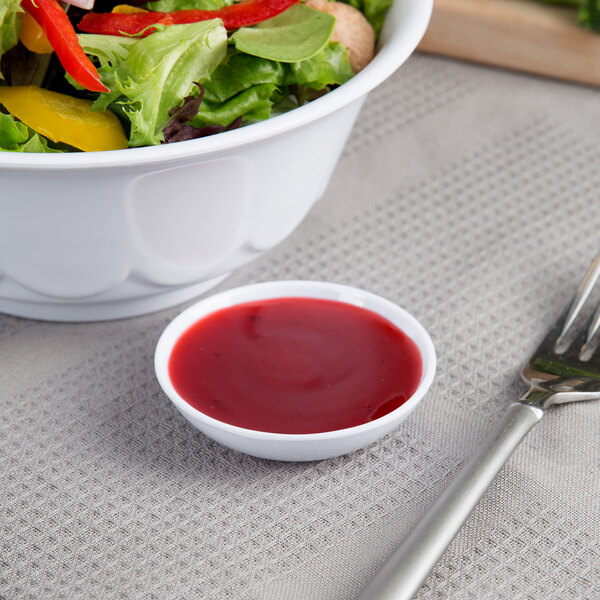 A bowl of salad with a fork and a Thunder Group white sauce dish filled with red sauce.