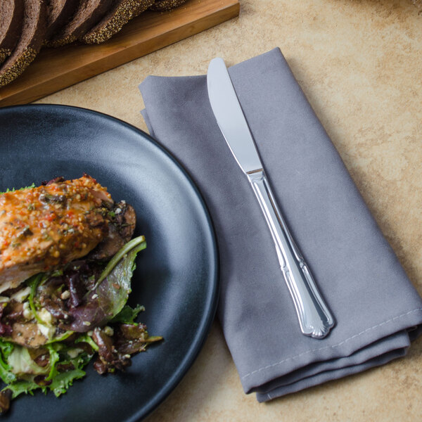 A plate of food next to a Walco Barony dinner knife.