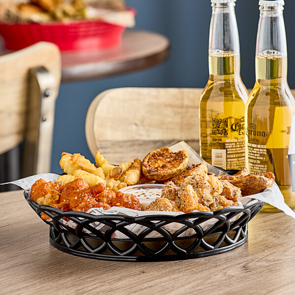 A black round plastic fast food basket filled with chicken nuggets and french fries on a table.