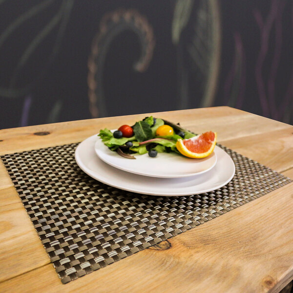 A plate of salad and fruit on a taupe and light green woven vinyl rectangle placemat.