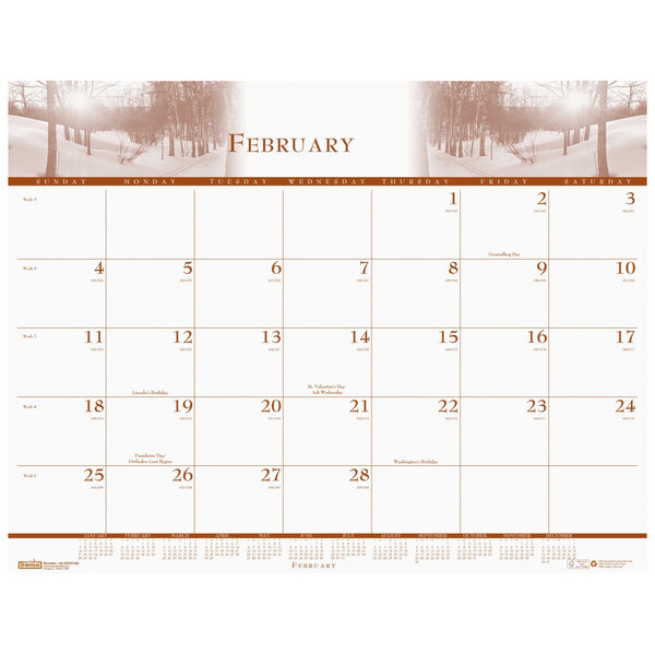 A House of Doolittle desk pad calendar with a nature scene of trees and snow.