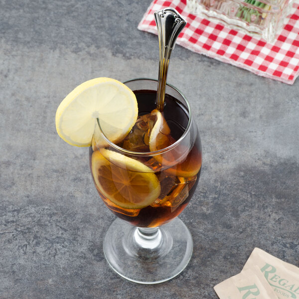 A glass of iced tea with lemon slices and a Walco stainless steel iced tea spoon.