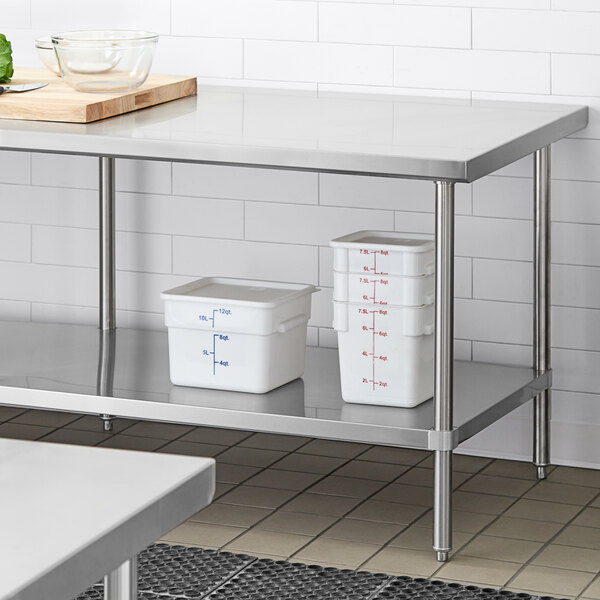 A Regency stainless steel work table undershelf with plastic containers on it.