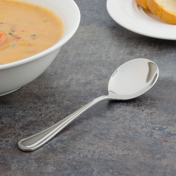 A Walco bouillon spoon in a bowl of soup on a table.