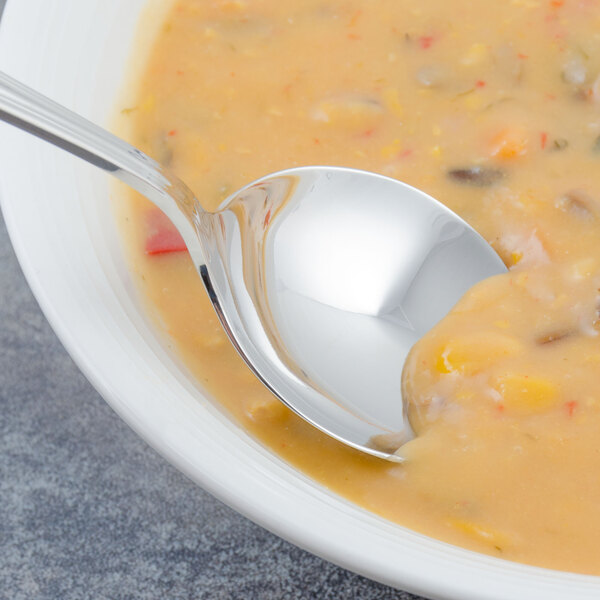 A Walco stainless steel bouillon spoon in a bowl of soup.