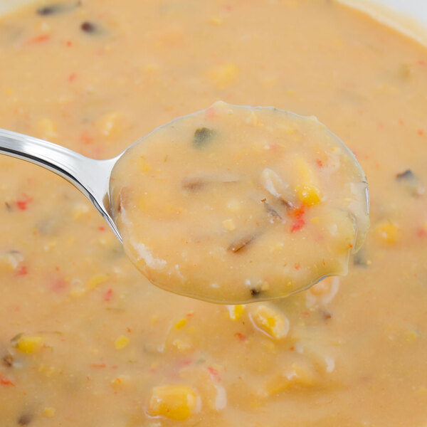 A Walco stainless steel bouillon spoon in a bowl of soup.