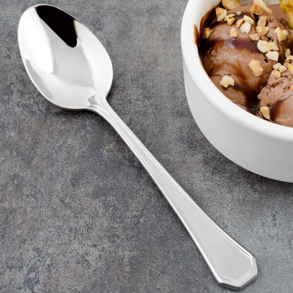 A Walco stainless steel dessert spoon next to a bowl of chocolate ice cream with nuts.