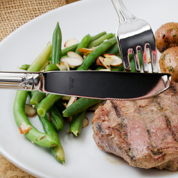 A plate of food with a Walco stainless steel table knife and fork.