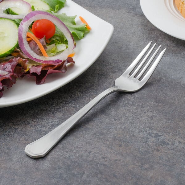 A Walco stainless steel salad fork next to a plate of salad.
