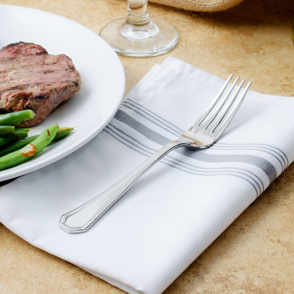 A Walco stainless steel dinner fork on a white plate of food.